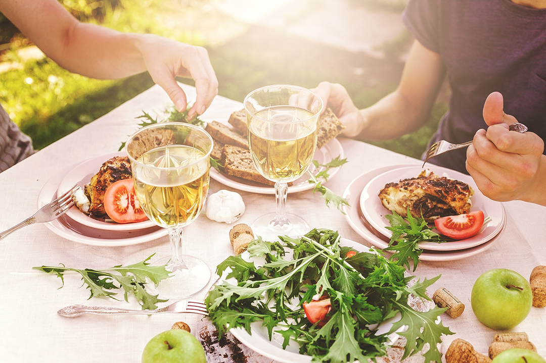 Twee mensen barbecueën en drinken witte wijn.